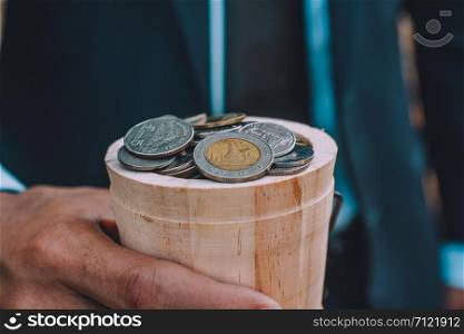 Hand holding coin and Coins stack on wood table money business finance concept
