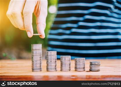Hand holding coin and Coins stack on wood table money business finance concept