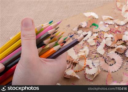 Hand holding Color Pencils over a notebook with pencil shavings