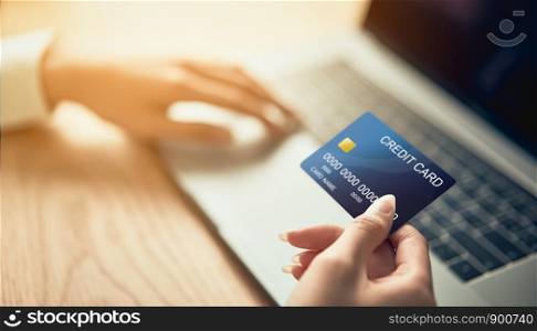Hand holding credit card and press laptop computer enter the payment code for the product. Pay online for convenience.
