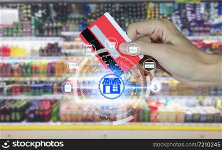 Hand holding credit card and Supermarket store abstract blurred background with online shopping icons technology, Online shopping concept
