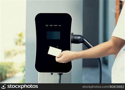 Hand holding credit card to pay public charging station and recharge her electric vehicle, symbolizing progressive lifestyle, combines e-wallet technology and sustainable transportation option.. Hand holding credit card and pay charging station to progressive EV car.