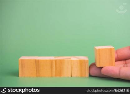 hand holding cube wood block blank on green background. copy space