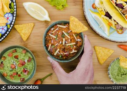 hand holding cup garnish with nacho near mexican food