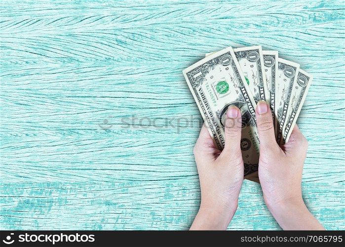 Hand holding dollar on wooden background texture pastel design pattern