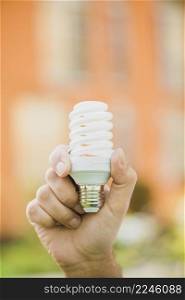 hand holding energy saving compact fluorescent light bulb outdoors
