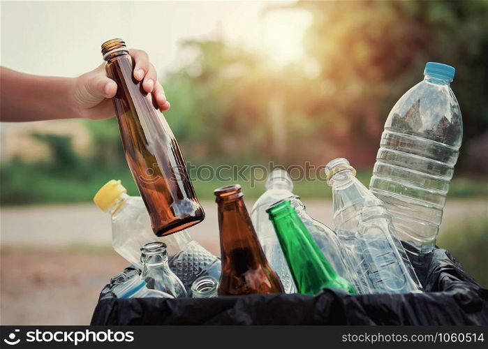 hand holding garbage bottle glass putting into recycle bag for cleaning
