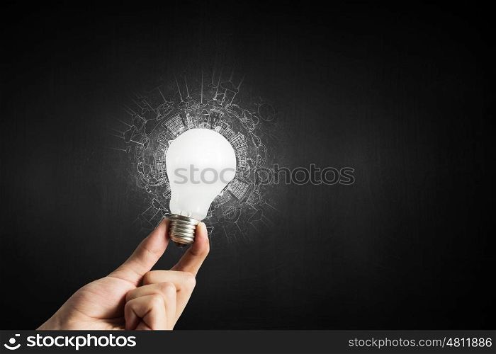 Hand holding glass glowing lightbulb in darkness. Glowing electric bulb