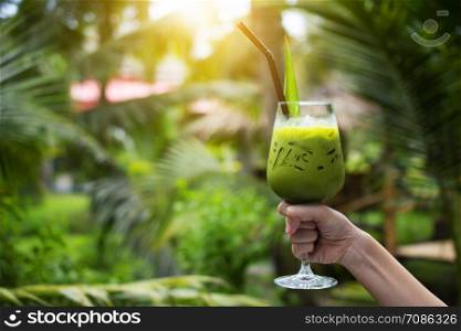 Hand holding glass of Green tea for drink and Green background