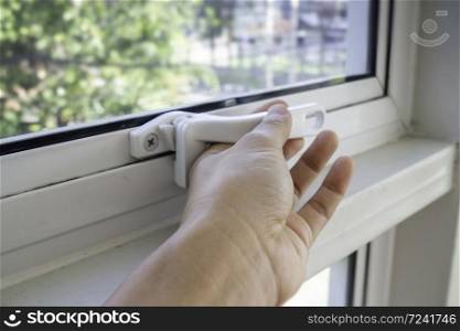 Hand holding glass window latch lever, stock photo