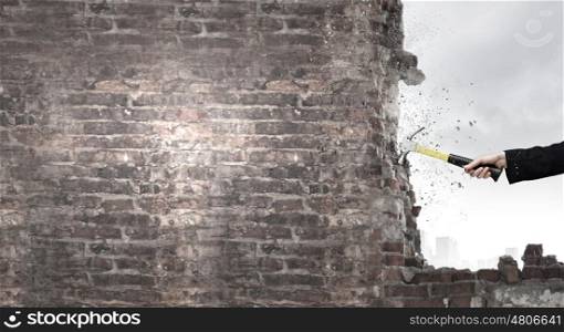 Hand holding hammer. Close up of businessman hand crashing brick wall