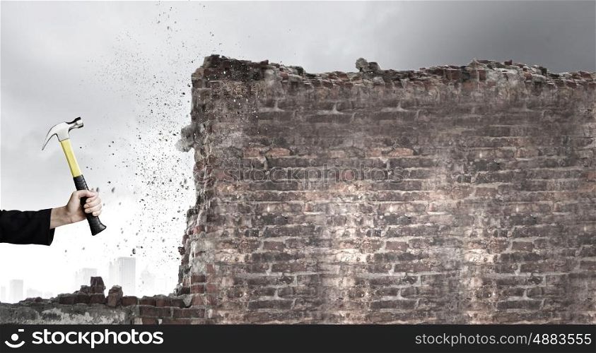 Hand holding hammer. Close up of businessman hand crashing brick wall