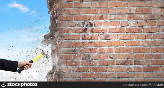 Hand holding hammer. Close up of businessman hand crashing brick wall