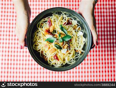 Hand holding homemade spaghetti on tablecloth