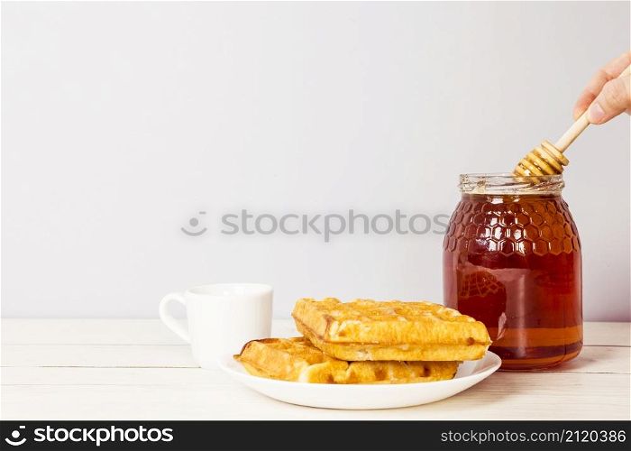 hand holding honey dipper from jar honey delicious breakfast table