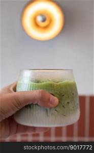 Hand holding iced matcha green tea, stock photo