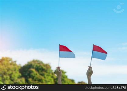 hand holding Indonesia flag on blue sky background. Indonesia independence day, National holiday Day and happy celebration concepts