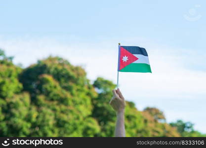 hand holding Jordan flag on nature background. Jordan Independence day and happy celebration concepts