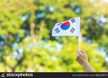 hand holding Korea flag on nature background. National Foundation, Gaecheonjeol, public Nation holiday, National Liberation Day of Korea and happy celebration concepts
