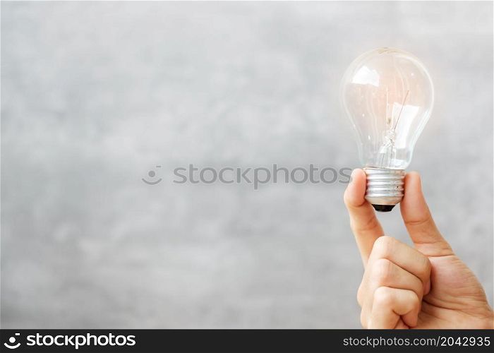 Hand holding light bulb on wall background. New Ideas, Creative, Innovation, Imagination, inspiration, Resolution, Strategy and goal concept