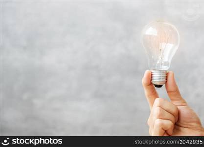 Hand holding light bulb on wall background. New Ideas, Creative, Innovation, Imagination, inspiration, Resolution, Strategy and goal concept
