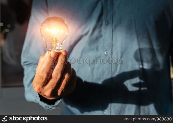 hand holding lightbulb with sunshine. concept saving energy power