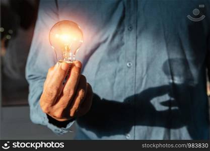 hand holding lightbulb with sunshine. concept saving energy power