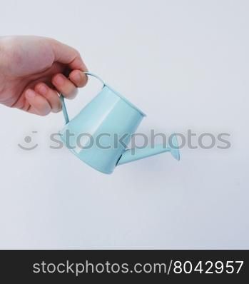 Hand holding little watering can on white background&#xA;