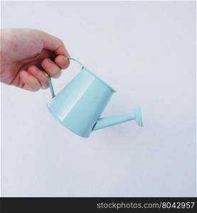 Hand holding little watering can on white background&#xA;