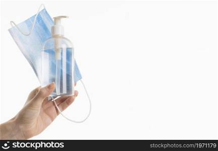 hand holding medical mask with hand sanitizer bottle. High resolution photo. hand holding medical mask with hand sanitizer bottle. High quality photo