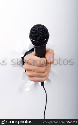 Hand holding microphone through hole in paper