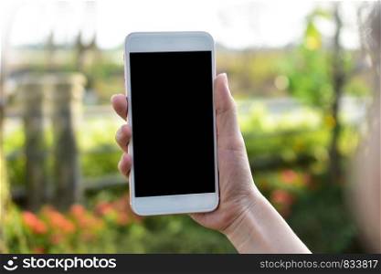 Hand holding Mobile Smart phone on Green Background