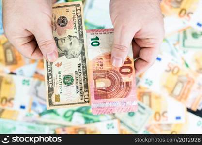 Hand holding money isolated on banknotes background. EURO and USD currency banknotes compared close up. Inflation, finance and business concept