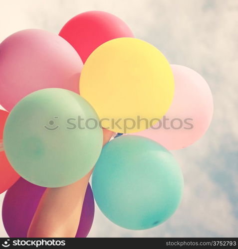 Hand holding multicolored balloons with retro filter effect