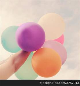 Hand holding multicolored balloons with retro filter effect