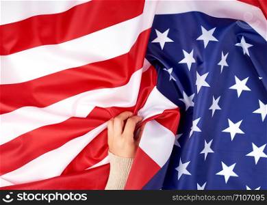 hand holding national textile flag of United States of America, surface in waves. Independence Day Background