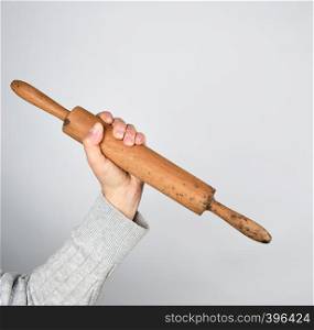 hand holding old wooden rolling pin on a gray background