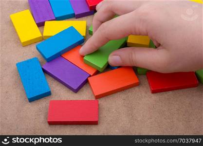 Hand holding one of the wooden blocks of various colors