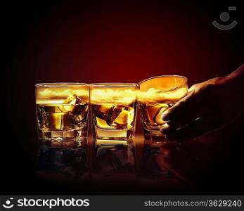 Hand holding one of three glasses of whiskey with ice and sky illustration in