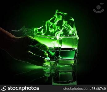 Hand holding one of two glasses of burning green absinth