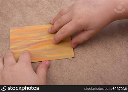 Hand holding painted note paper on brown background