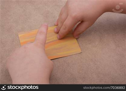 Hand holding painted note paper on brown background