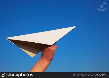 Hand holding paper plane against blue sky
