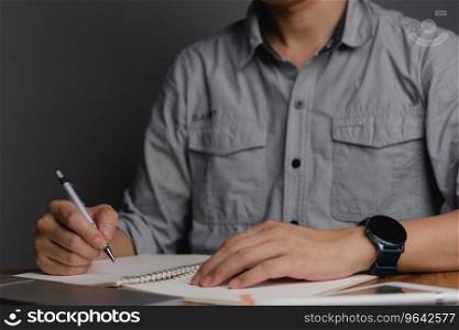 hand holding pen with writing or planning journal on note book in office