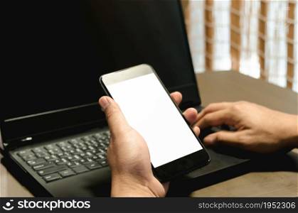 hand holding phone mockup image blank screen computer laptop for advertising text in workplace desk at office.