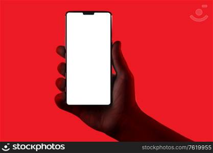 Hand holding phone. Silhouette of male hand holding smartphone isolated on red background. Bezel-less screen is cut with clipping path.. Hand holding phone.