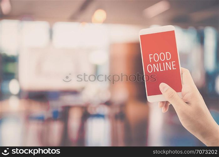 Hand holding phone with food order online with blur of restaurant background, order food online business concept.