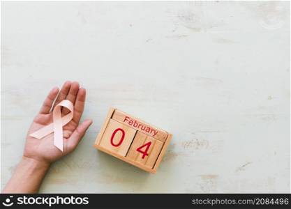 hand holding pink awareness ribbon 4th february wooden box backdrop
