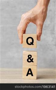 Hand holding Q and A word with wooden block. FAQ( frequency asked questions), Answer, Question Ask, Information, Communication and Brainstorming Concepts
