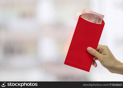 Hand holding red envelope or Ang pao. Chinese Lunar New Year celebrations concept